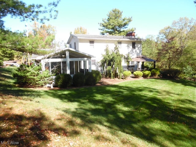 rear view of property with a sunroom and a lawn