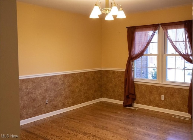 120 Woodcrest Dr, Marietta, OH 45750 - empty room featuring wood finished floors, a chandelier, a wainscoted wall, and baseboards