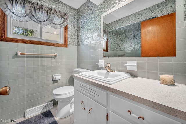 bathroom featuring backsplash, vanity, toilet, and tile walls