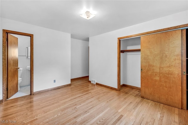 unfurnished bedroom featuring ensuite bath, a closet, and light hardwood / wood-style flooring