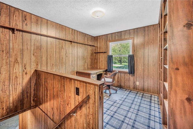 unfurnished office featuring a textured ceiling and wood walls