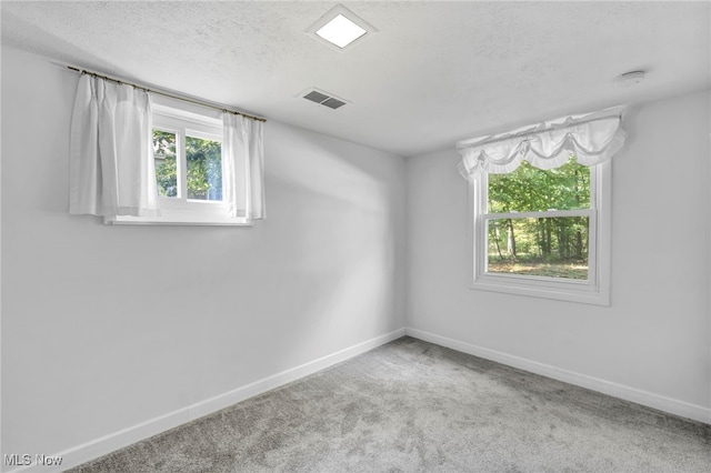 carpeted empty room featuring a textured ceiling