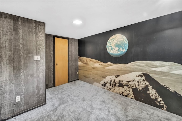 unfurnished bedroom with light colored carpet and wooden walls