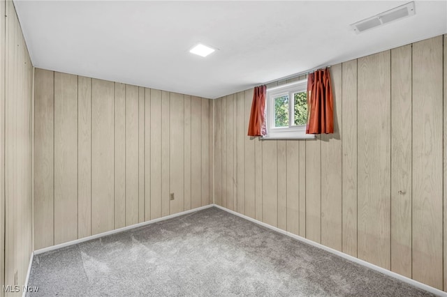 spare room with carpet and wooden walls