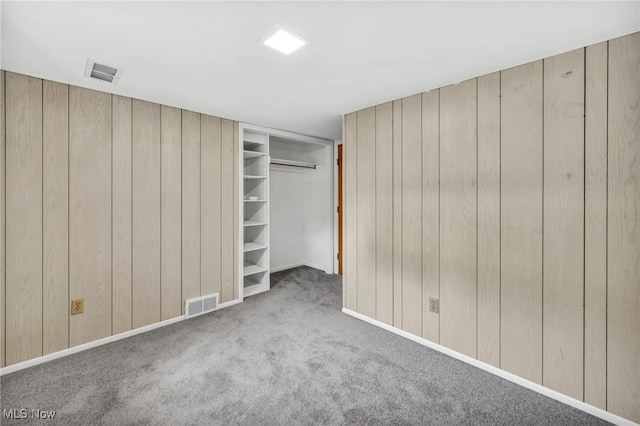 unfurnished bedroom with carpet flooring and wood walls