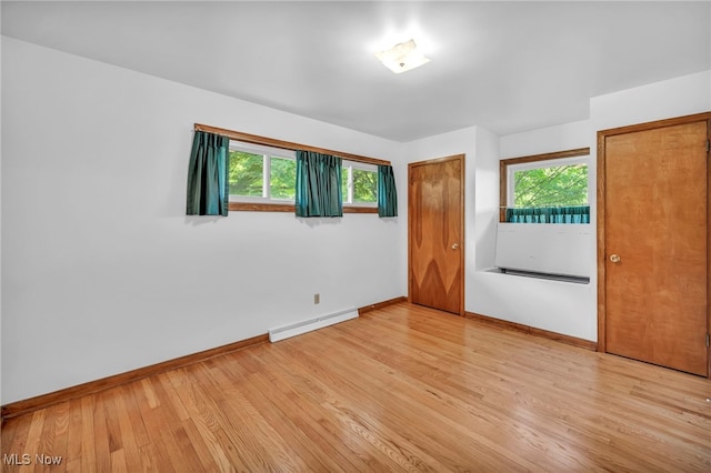 unfurnished bedroom with light hardwood / wood-style flooring and a baseboard heating unit