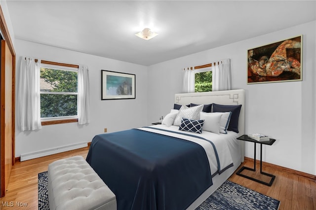 bedroom with light hardwood / wood-style flooring and a baseboard heating unit