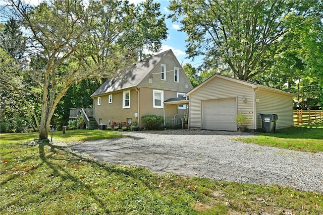 view of front of property with a front yard, a garage, an outbuilding, and central AC