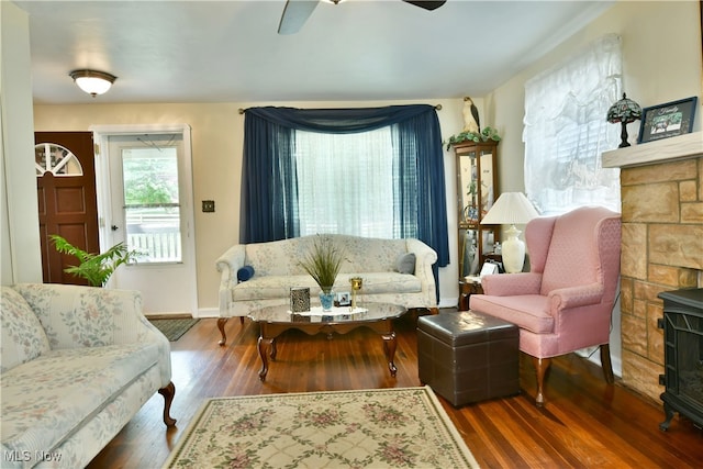 living room featuring a wood stove, ceiling fan, and dark wood-type flooring