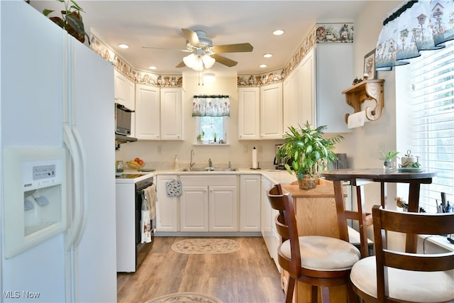 kitchen featuring light wood-type flooring, sink, white appliances, and a wealth of natural light