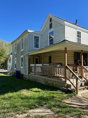 back of house featuring a lawn and covered porch