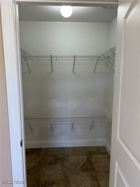 walk in closet with dark tile patterned floors