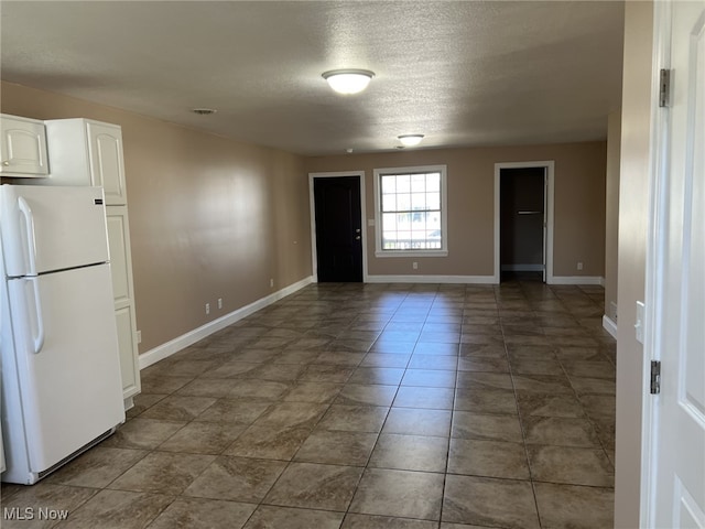 tiled empty room featuring a textured ceiling