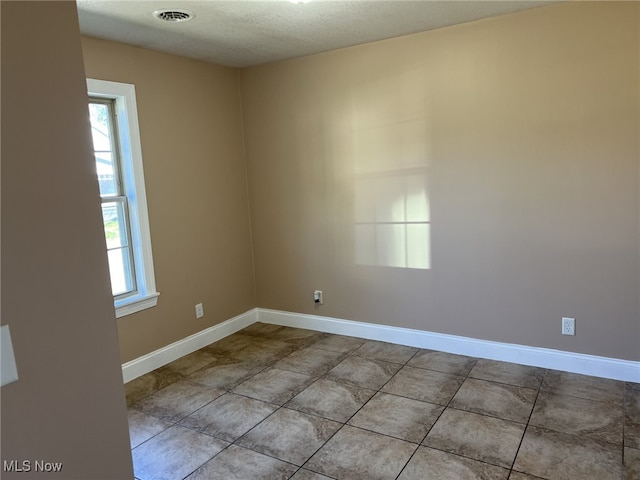 unfurnished room with light tile patterned flooring and a textured ceiling