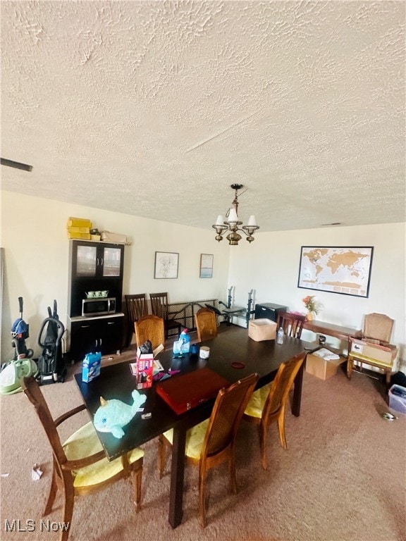 dining space with a notable chandelier, carpet floors, and a textured ceiling