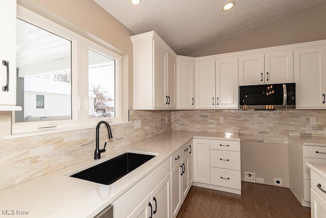 kitchen with white cabinetry, decorative backsplash, dark hardwood / wood-style flooring, vaulted ceiling, and sink