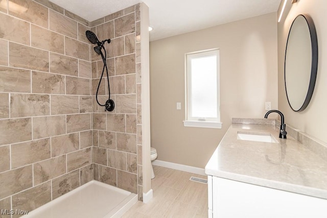 bathroom featuring toilet, vanity, and a tile shower