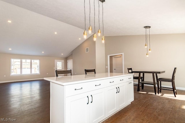 kitchen featuring decorative light fixtures, dark wood-type flooring, white cabinetry, and a center island