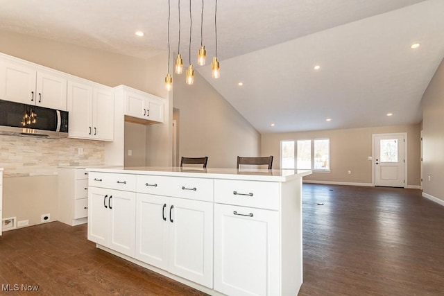 kitchen with tasteful backsplash, dark hardwood / wood-style floors, hanging light fixtures, white cabinets, and a center island