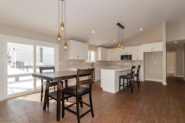 dining area featuring lofted ceiling, dark hardwood / wood-style floors, and sink