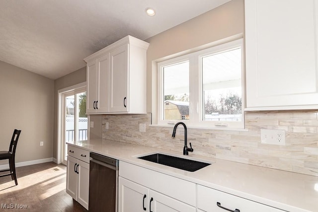 kitchen featuring hardwood / wood-style floors, black dishwasher, decorative backsplash, white cabinets, and sink