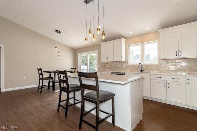 kitchen with a center island, a kitchen breakfast bar, hanging light fixtures, white cabinets, and sink