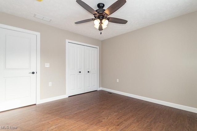 unfurnished bedroom featuring dark wood-type flooring, ceiling fan, and a closet