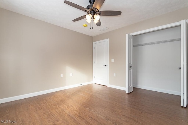 unfurnished bedroom featuring ceiling fan, dark hardwood / wood-style flooring, and a closet