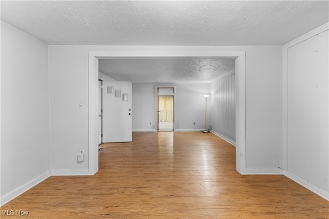 spare room featuring a textured ceiling and light hardwood / wood-style floors