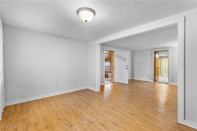 unfurnished room with a textured ceiling and light hardwood / wood-style flooring