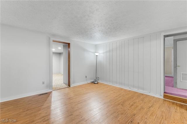 spare room featuring light hardwood / wood-style floors and a textured ceiling