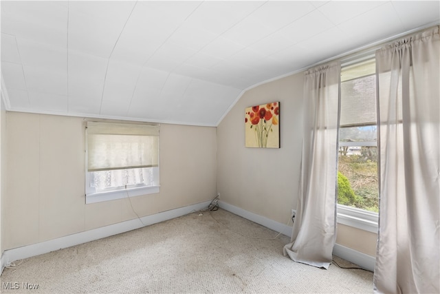 carpeted spare room featuring vaulted ceiling