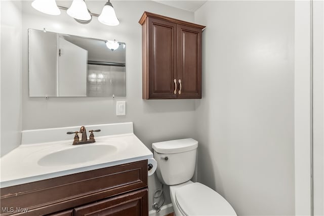 bathroom with a shower with door, vanity, and toilet