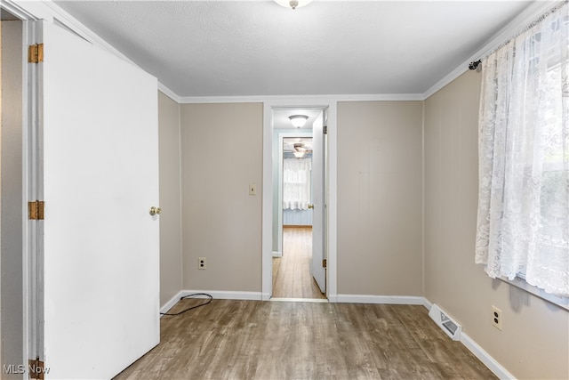 spare room with ornamental molding, light hardwood / wood-style flooring, a textured ceiling, and ceiling fan