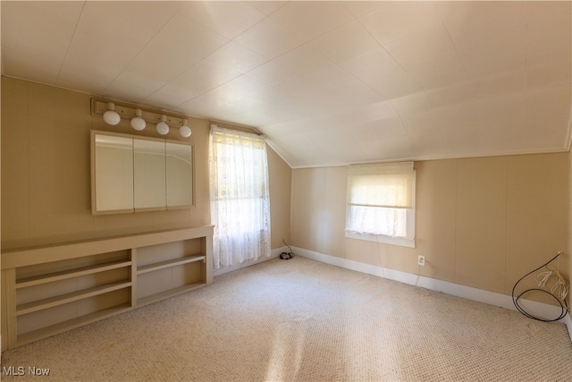 bonus room with lofted ceiling and light colored carpet