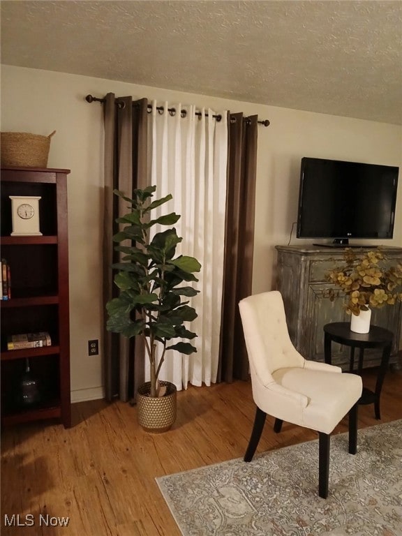 sitting room with hardwood / wood-style floors and a textured ceiling