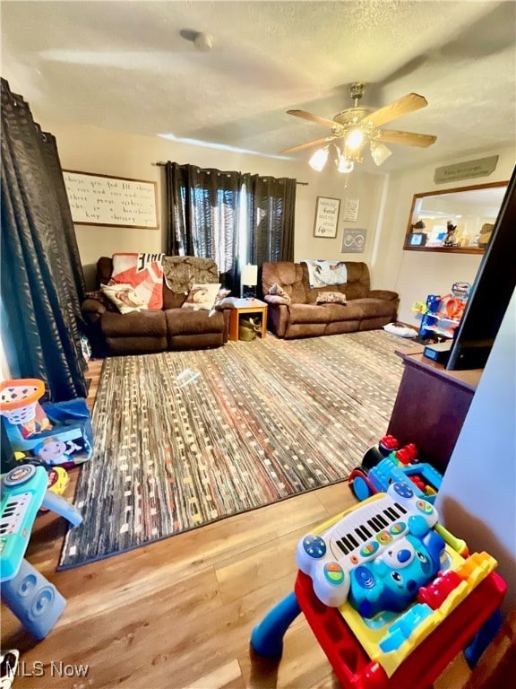 living room with ceiling fan, hardwood / wood-style floors, and a textured ceiling