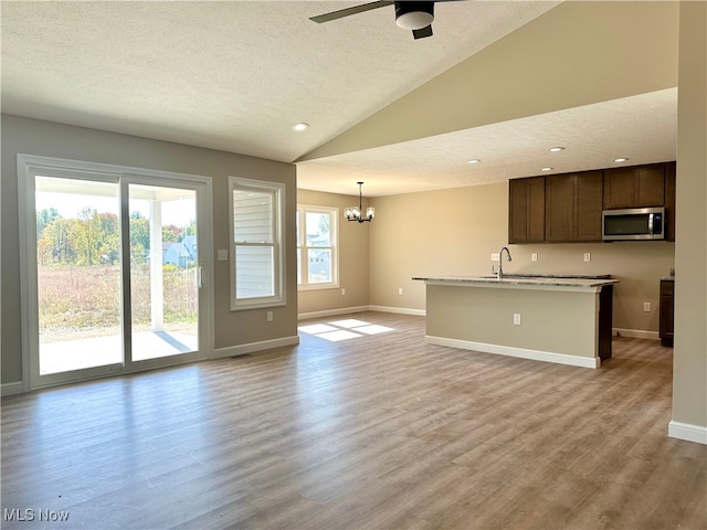 kitchen with pendant lighting, dark brown cabinetry, vaulted ceiling, and light hardwood / wood-style floors