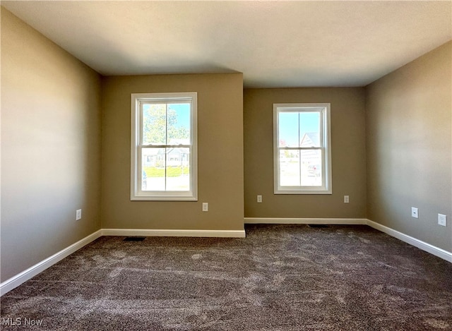 spare room featuring dark carpet