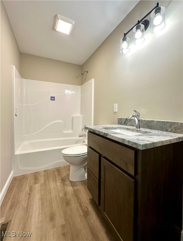 full bathroom featuring wood-type flooring,  shower combination, vanity, and toilet