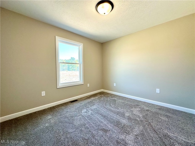 carpeted empty room featuring a textured ceiling