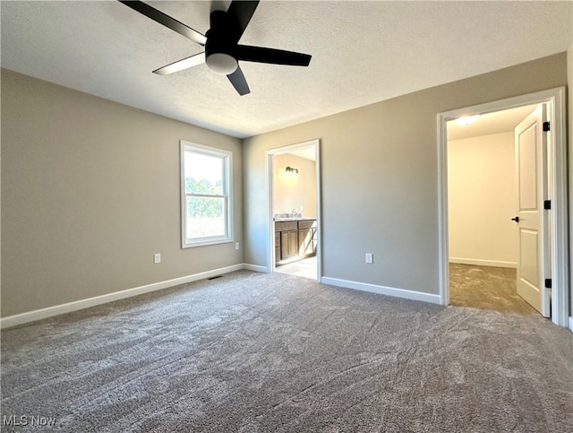 unfurnished bedroom with carpet flooring, ensuite bathroom, a textured ceiling, and ceiling fan