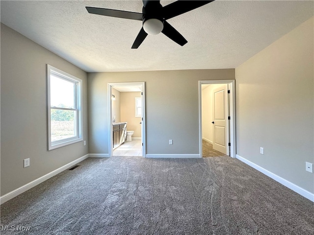 unfurnished bedroom with carpet floors, ensuite bathroom, a textured ceiling, and ceiling fan