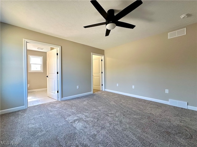 unfurnished bedroom featuring ceiling fan, connected bathroom, a textured ceiling, and light carpet