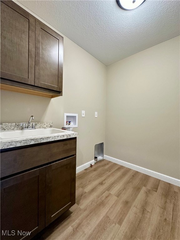 laundry room featuring hookup for a washing machine, a textured ceiling, light hardwood / wood-style flooring, and sink