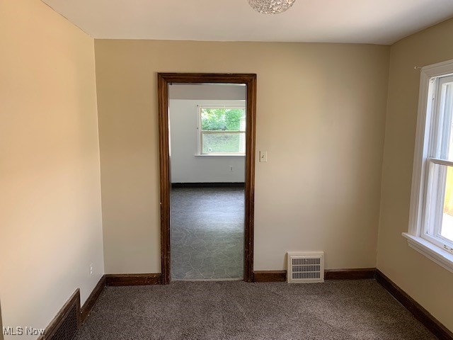 spare room with dark carpet and a healthy amount of sunlight