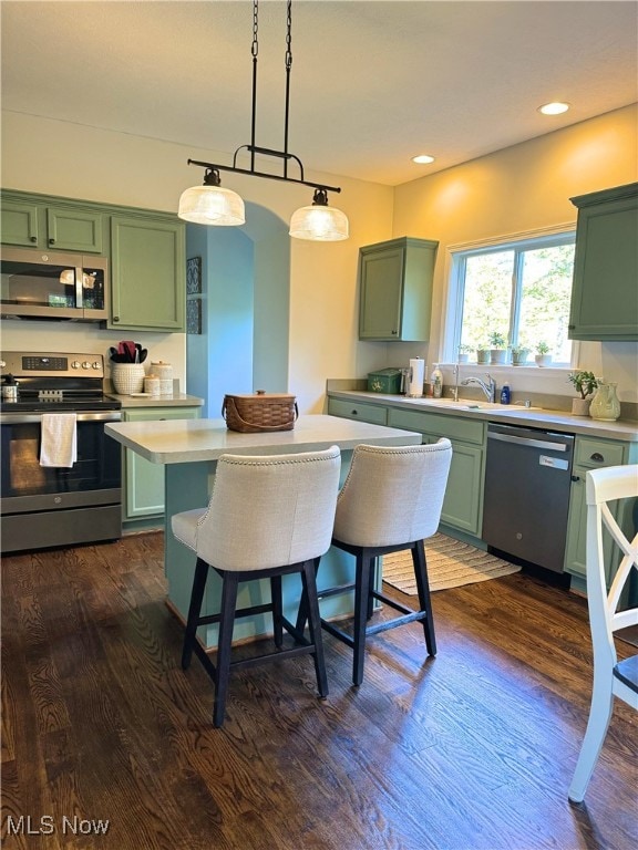 kitchen featuring stainless steel appliances, dark hardwood / wood-style floors, and green cabinets