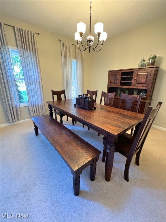 dining space with light carpet and a notable chandelier