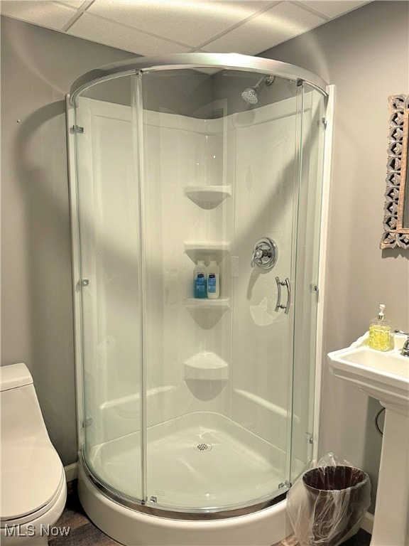 bathroom featuring a drop ceiling, toilet, and an enclosed shower