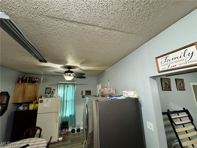 kitchen with wood-type flooring, white refrigerator, a textured ceiling, ceiling fan, and stainless steel fridge